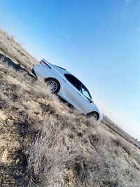 Low angle view of car on field against clear blue sky