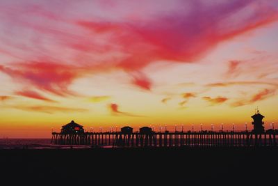 Silhouette pier on beach against sky during sunset