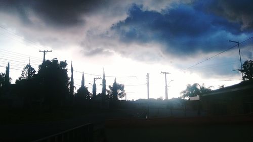 Silhouette trees and electricity pylon against sky during sunset