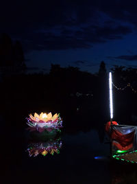 Illuminated boat in lake against sky at night