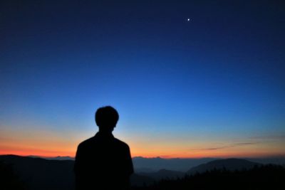 Silhouette man looking at sunset