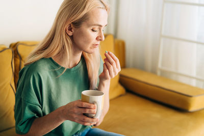 Sick unhappy woman holding a pill. copy space