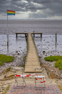 Deck chairs on beach against sky