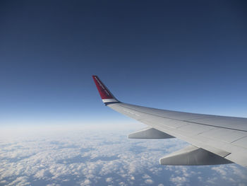 Airplane wing flying over clouds