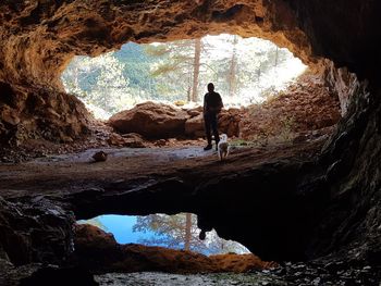 Rear view of men standing on rock in cave