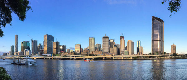 Sea and buildings in city against clear sky