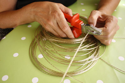 Cropped hands cutting wire at table