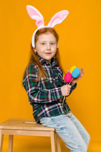 Portrait of cute girl playing with toys against yellow background