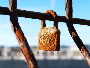 Close-up of padlock on fence against sky