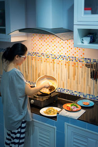 Woman serving food in plate at home