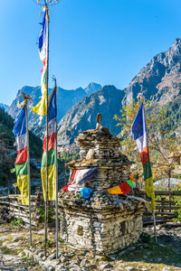 Flags hanging on clothesline by mountain against sky