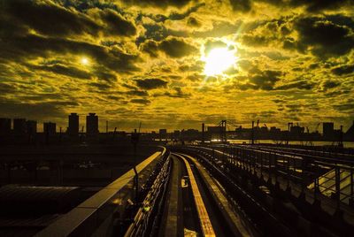 Railroad tracks in city against sky at sunset