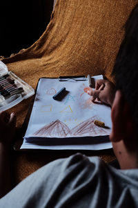 Midsection of kid drawing random stuff in paper on table