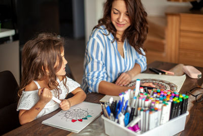 Mother and daughter drawing while sitting at home