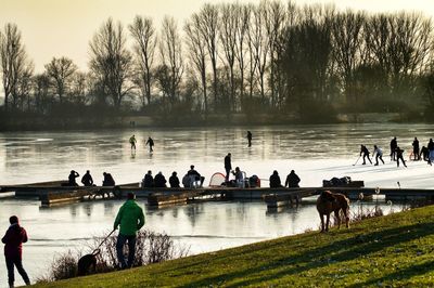 Birds perching on people by lake