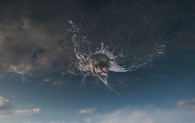 A man dives into a cloudy sky.