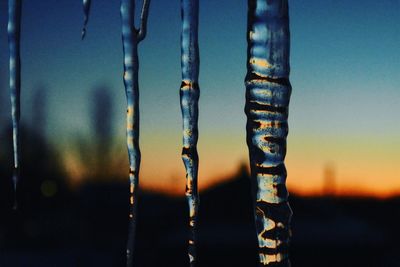 Close-up of icicles against sky during winter