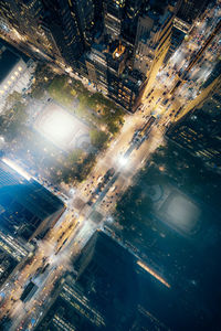 High angle view of illuminated street amidst buildings in city at night