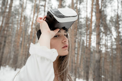 Woman wearing virtual reality simulator against trees outdoors