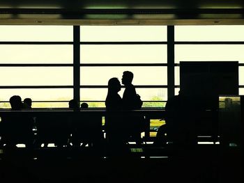 Silhouette people standing in glass window