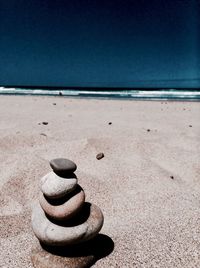 Stack of pebbles on beach against sky