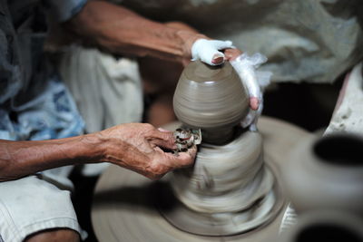 Midsection of man making pottery in workshop