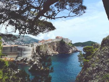 Buildings by sea against sky