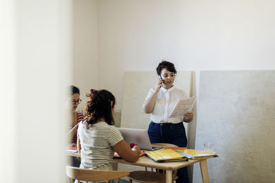 Woman speaking on phone working with colleagues in workspace