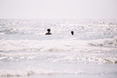 People in sea against sky