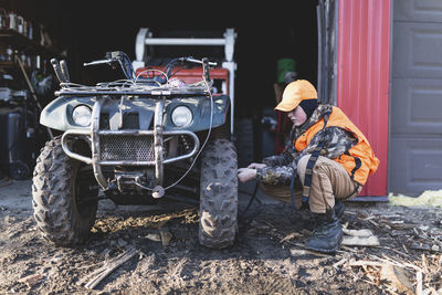 Side view of boy filling quadbike tire with air at fuel station