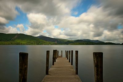 Wooden pier over lake against sky