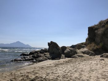 Rock formation on beach against clear blue sky