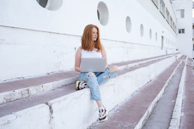 Full length of woman using laptop using laptop outdoors