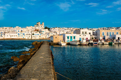 View of buildings by sea against blue sky