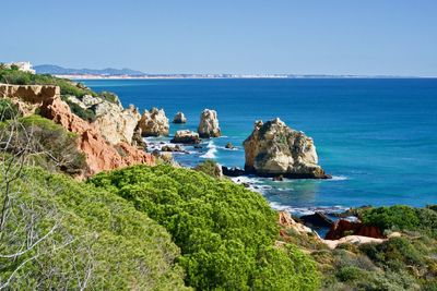 Rocks by sea against clear blue sky