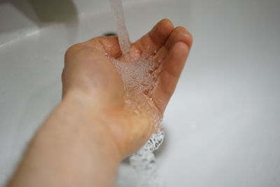 Close-up of hand touching water in bathroom