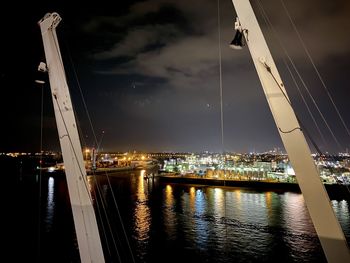 Illuminated harbor by river against sky at night