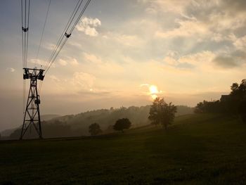 Electricity pylon on field against sky during sunset