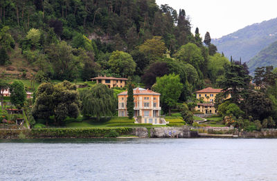 Houses by river and buildings against mountain