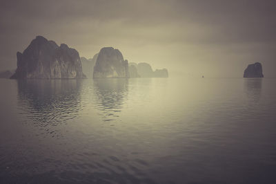 Mountains in sea against sky during sunset