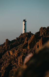 Lighthouse by sea against clear sky