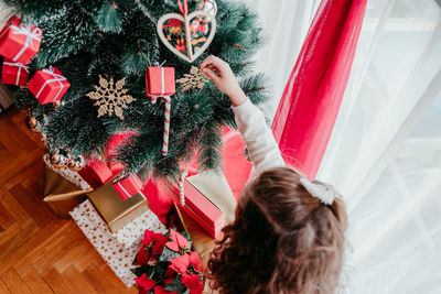High angle view of girl decorating christmas tree at home