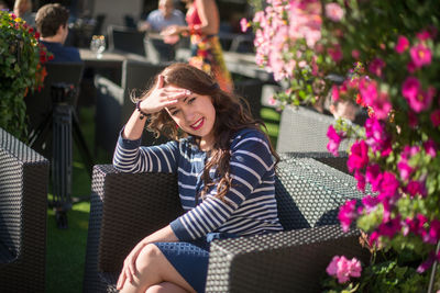 Woman sitting on mobile phone while looking away outdoors