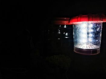 Close-up of illuminated electric lamp on table in dark room