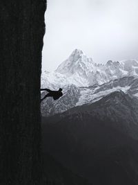 Silhouette man climbing on rocky mountain against clear sky