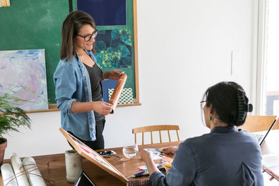 Female design professionals discussing while working together in home office