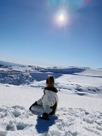 Rear view of woman sitting on snow during winter