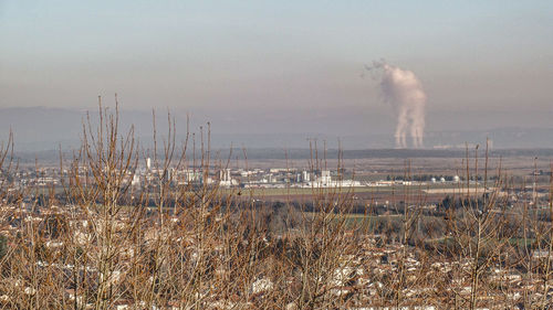 Smoke emitting from chimney on field against sky