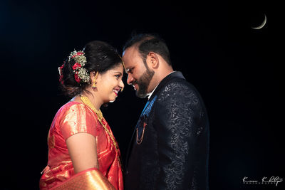 Young couple kissing against black background