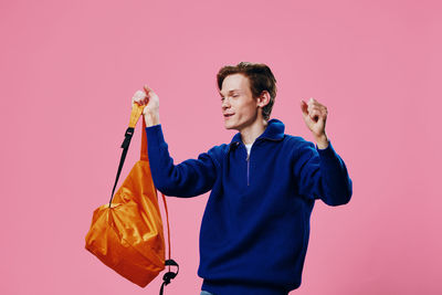 Portrait of young woman holding gift against yellow background